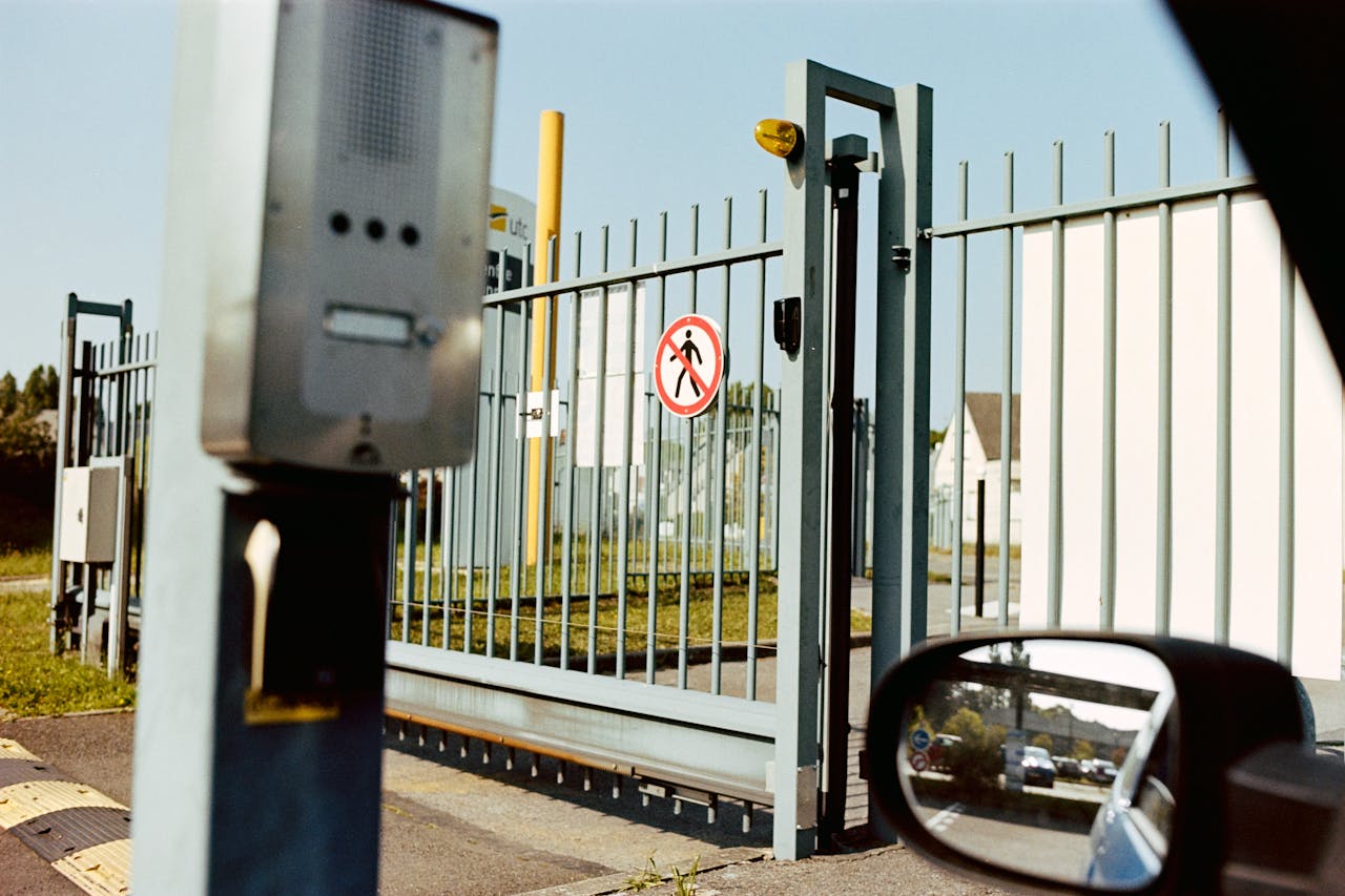 Home Security gate with no pedestrian sign and intercom, view from a car window.
